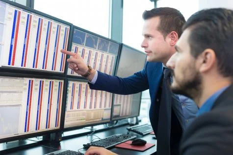Two traders looking at statistics on their computer screens